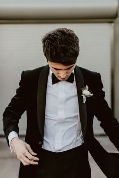 a man in a tuxedo and bow tie is holding his hand on his hip