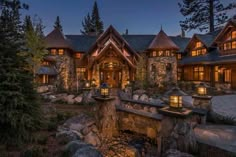 a large stone house with lots of windows and lights on it's front entrance