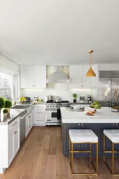 a large kitchen with white cabinets and wood flooring, along with an island in the middle