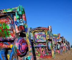 colorfully painted trucks are lined up on the dirt