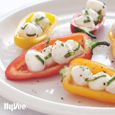 several peppers with mozzarella cheese and herbs on them sitting on a white plate