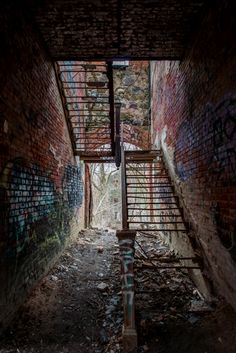 an abandoned stairway in the middle of a brick building with graffiti on it's walls