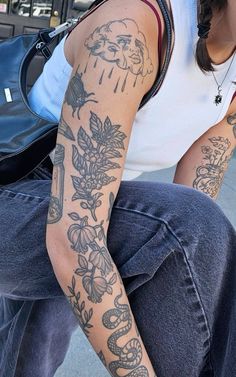 a woman sitting on the ground with tattoos on her arm