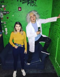 a man and woman standing in front of a green wall