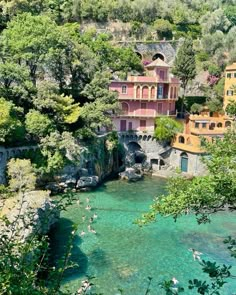 the water is crystal blue and clear with people swimming in it, surrounded by lush green trees