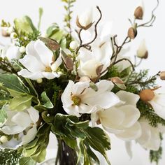 a vase filled with white flowers and greenery