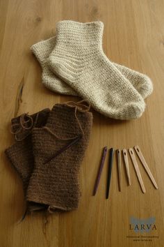 some knitting supplies are laying on a wooden table next to a pair of gloves and needles