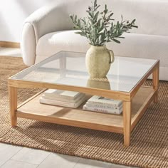 a coffee table with a vase on top and books under it in front of a couch