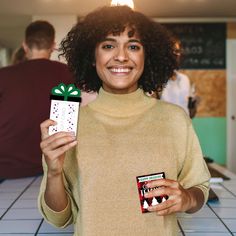 a woman holding a small gift box with a red bow on it and smiling at the camera