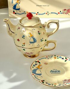 a tea pot and saucer are sitting on a table with a sign in the background