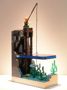 a lego model of a man fishing in the ocean with corals and seaweed