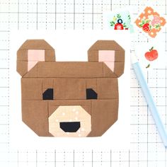 a piece of fabric with a bear's head on it next to a pencil