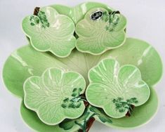 four green leaf shaped dishes sitting on top of each other