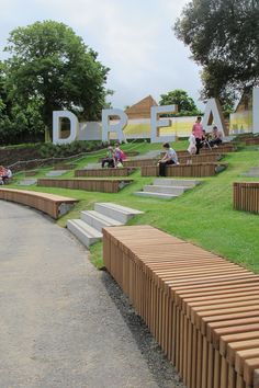 people are sitting on benches in the grass near a sign that reads,'dream '