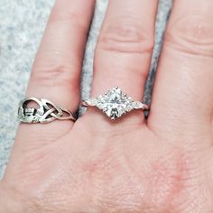 a woman's hand with two rings on it and an engagement ring in the middle