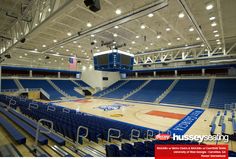 an empty basketball court with blue seats and lights