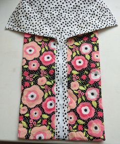 a polka dot shirt with pink flowers and black dots on the collar is laying on a table