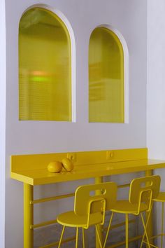 two yellow chairs sitting next to each other in front of a counter