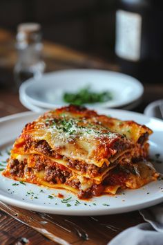 lasagna with meat sauce and parmesan cheese on white plate sitting on wooden table