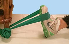 a pair of feet with green shoelaces attached to them, next to a wooden structure