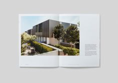 an open book showing the inside pages of a house with trees and bushes in front of it