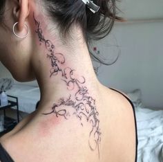 a woman with a tattoo on her neck and behind her ear is a flower vine