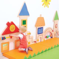 a young child playing with a wooden toy house