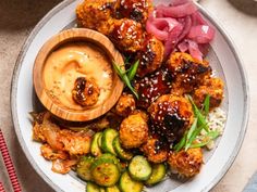 a white plate topped with meat and veggies next to a bowl of sauce