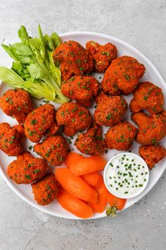 a white plate topped with meatballs, carrots and lettuce next to dip