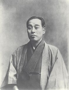 an old black and white photo of a man in a kimono looking at the camera