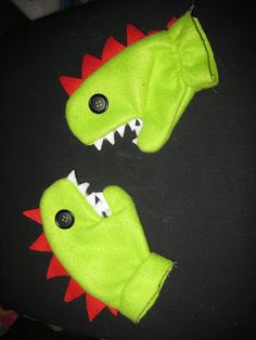 two green stuffed animals with red and white teeth on black fabric, facing each other