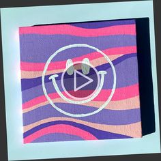 an image of a video play button painted on a piece of paper with pink and purple stripes