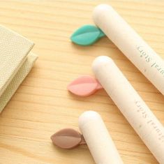 three pens are sitting on a table next to an open book and some other items