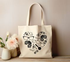 a white tote bag sitting on top of a wooden table next to a vase with flowers