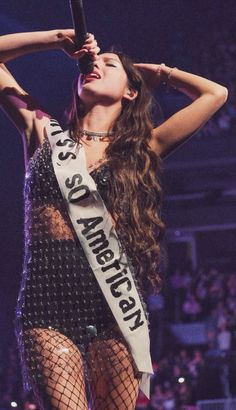 a woman is standing on stage with her hands behind her head