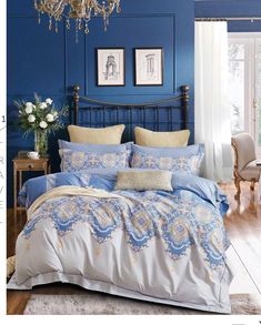 a bedroom with blue walls and white bedding, chandelier and pictures on the wall