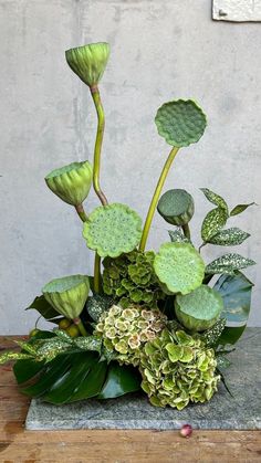 a vase filled with green flowers and greenery