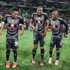 three soccer players are standing on the field with their hands in their pockets and smiling