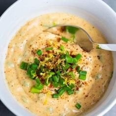 a white bowl filled with soup topped with green onions and garnished with parsley