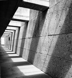 an empty walkway lined with concrete blocks and shadows on the wall, in black and white