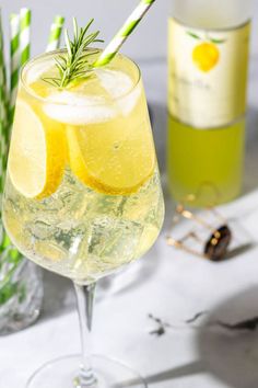 a glass filled with lemonade next to a bottle of wine and two straws