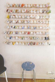 a chair and table in front of a wall with many cups on the bottom shelf