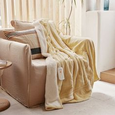 a living room with a couch and chair covered in a blanket next to a window