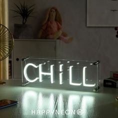 a neon sign that says chill on it sitting on a table next to a fan