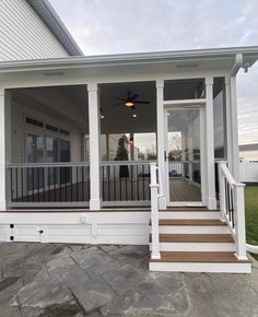 a porch with steps leading up to the front door and covered in white sidings