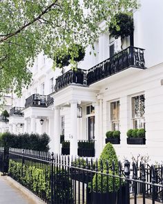 a white house with black iron fence and trees