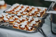 several trays of food on a table with silver utensils and other items