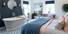 a large white bath tub sitting next to a bed in a room with blue walls