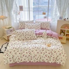 a bed with pink and white flowers on it in a room next to a window