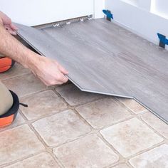 a man laying vinyl flooring on the ground